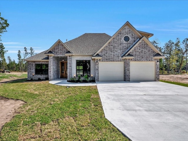 french country home with brick siding, a garage, a front yard, and concrete driveway
