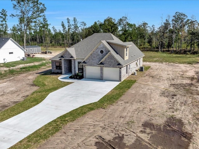 view of front of house with a front yard, driveway, central AC unit, and stone siding