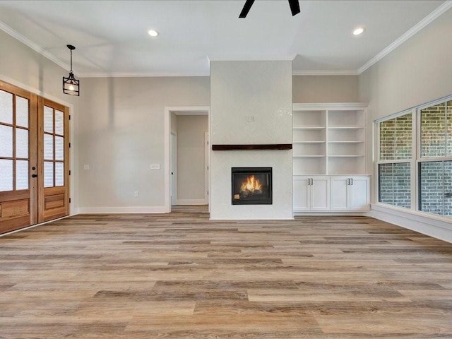 unfurnished living room with ornamental molding, a glass covered fireplace, baseboards, recessed lighting, and light wood finished floors