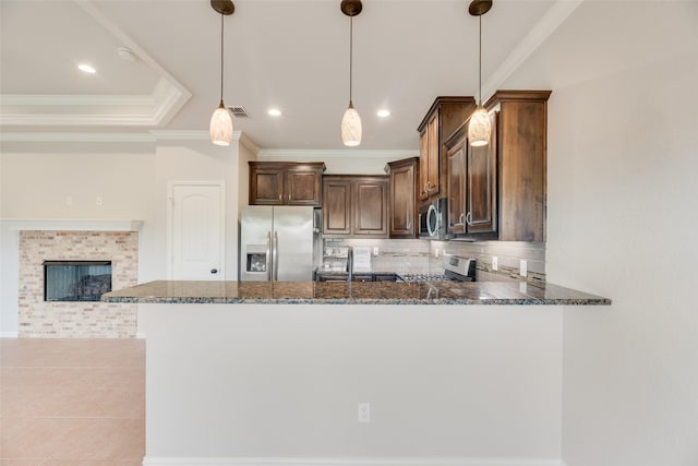 kitchen featuring dark stone counters, appliances with stainless steel finishes, ornamental molding, and a sink