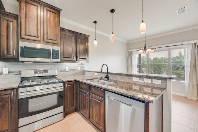 kitchen featuring appliances with stainless steel finishes, tasteful backsplash, a sink, light tile patterned floors, and a peninsula