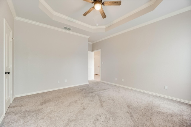 spare room with ceiling fan, visible vents, crown molding, a tray ceiling, and carpet flooring