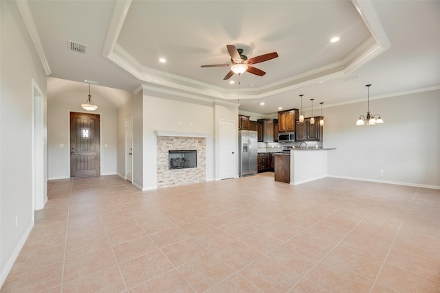 unfurnished living room featuring visible vents, crown molding, light tile patterned floors, ceiling fan with notable chandelier, and a tray ceiling