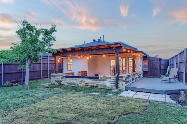 4045 Sun King Ln, Frisco, TX 75033 - back of house at dusk featuring a fenced backyard, a lawn, a deck, and brick siding