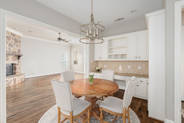 2231 Morning Dew Ct, Allen, TX 75013 - dining area featuring a chandelier, a stone fireplace, dark wood finished floors, ceiling fan, and crown molding
