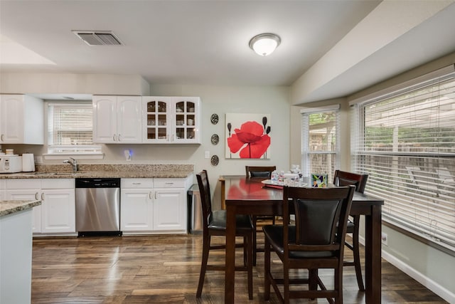 kitchen with stainless steel dishwasher, visible vents, a wealth of natural light, and light stone counters