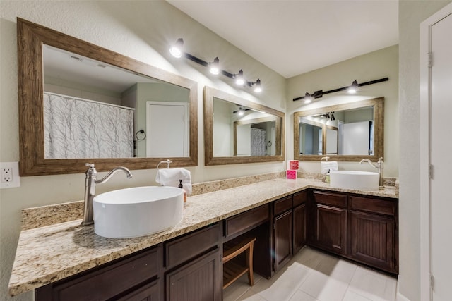 full bathroom with double vanity, a sink, and tile patterned floors