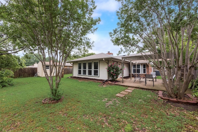 back of property featuring an outbuilding, a patio area, a fenced backyard, a storage unit, and a yard