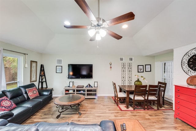 living room with visible vents, a ceiling fan, light wood-style floors, and vaulted ceiling