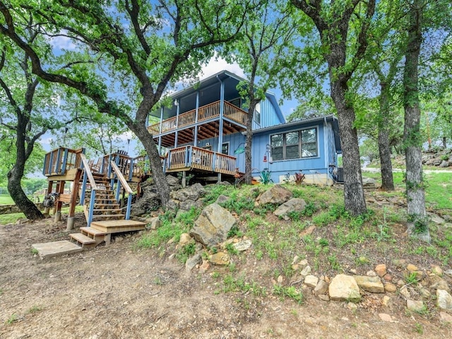 back of house with stairs, board and batten siding, and a wooden deck