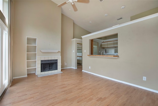 unfurnished living room with ceiling fan, visible vents, a fireplace, high vaulted ceiling, and baseboards