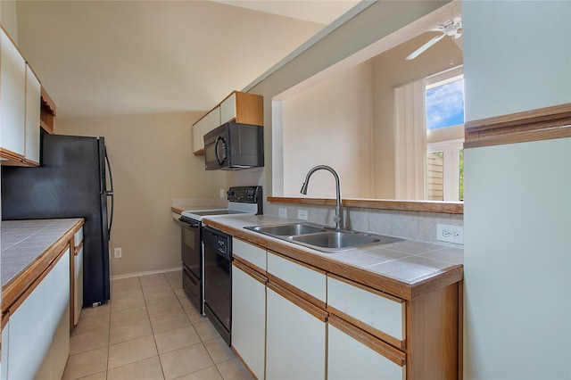 kitchen featuring tile countertops, white cabinetry, a sink, and black appliances