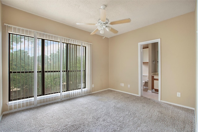 empty room with carpet flooring, a textured ceiling, ceiling fan, and baseboards