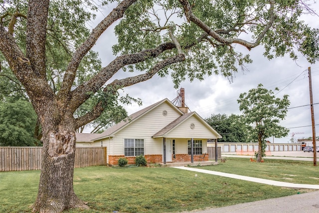 bungalow-style home featuring fence, a chimney, a front lawn, and brick siding