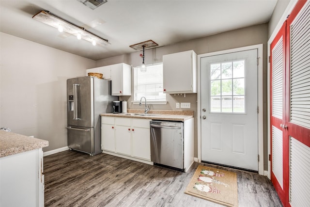kitchen featuring dark wood-type flooring, light countertops, white cabinets, a sink, and appliances with stainless steel finishes
