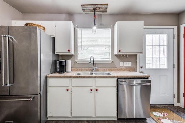 kitchen featuring a sink, light countertops, stainless steel appliances, decorative light fixtures, and white cabinetry