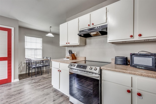 kitchen with light wood-type flooring, light countertops, white cabinetry, under cabinet range hood, and stainless steel range with electric cooktop