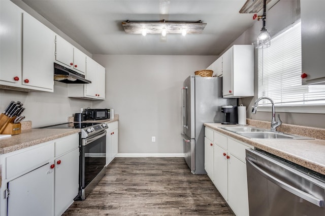 kitchen with under cabinet range hood, white cabinetry, appliances with stainless steel finishes, and a sink