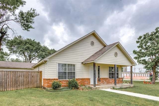 bungalow-style house featuring a porch, brick siding, fence, and a front lawn