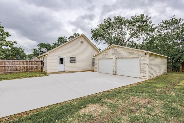 view of home's exterior with a lawn, fence, an outbuilding, and a detached garage