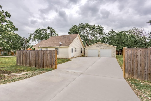 view of side of home featuring an outdoor structure, a garage, a lawn, and fence