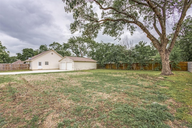 view of yard featuring a fenced backyard, a detached garage, an outdoor structure, and a patio