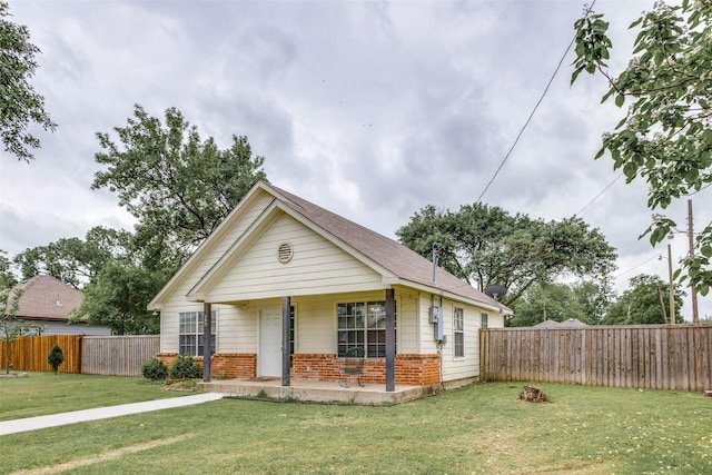 bungalow-style house with a fenced backyard, covered porch, a front lawn, and brick siding