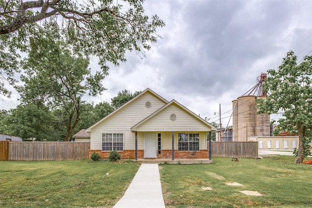 bungalow-style house featuring brick siding, fence, and a front yard