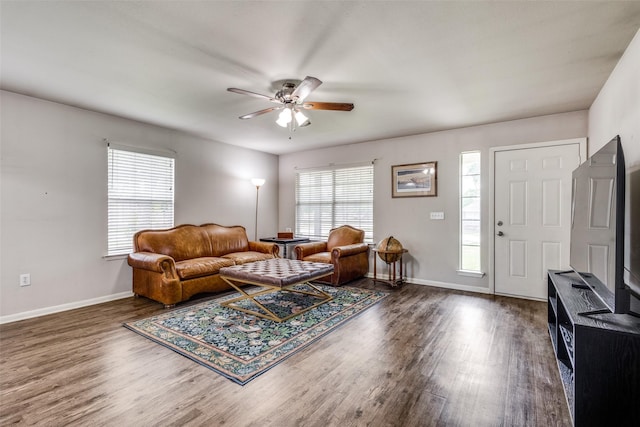 living area with baseboards, ceiling fan, and wood finished floors