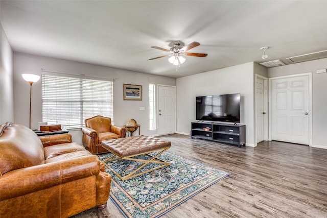 living area with baseboards, attic access, ceiling fan, and wood finished floors