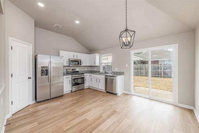 kitchen with a sink, light wood-style floors, stainless steel appliances, and lofted ceiling