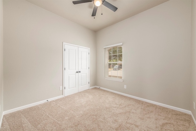 carpeted empty room featuring baseboards and ceiling fan
