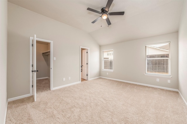 unfurnished bedroom with carpet floors, baseboards, lofted ceiling, and a walk in closet