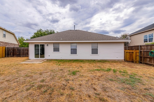 back of house featuring a lawn and a fenced backyard
