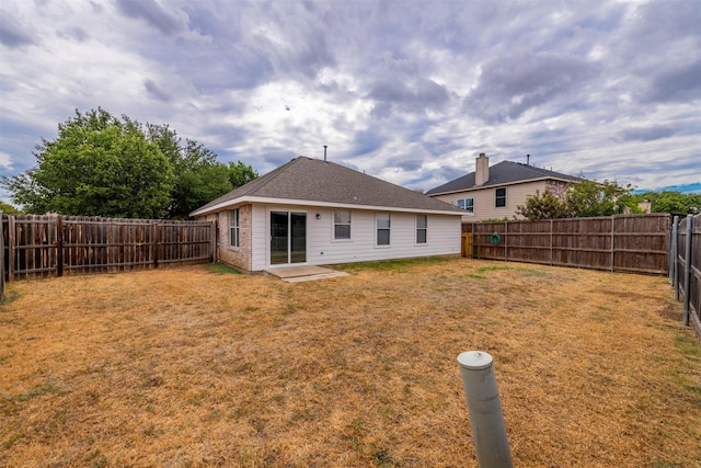 back of property featuring a fenced backyard and a yard