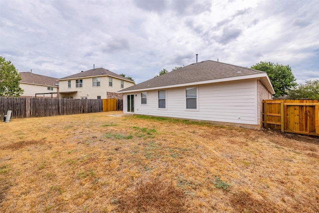 rear view of house with a fenced backyard and a yard