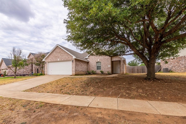 view of front of home featuring fence, central AC, brick siding, a garage, and driveway