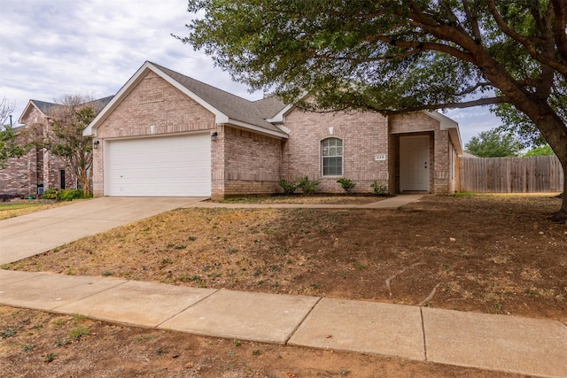 view of front of property featuring brick siding, an attached garage, fence, and concrete driveway