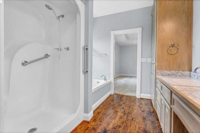 bathroom featuring vanity, a shower stall, a garden tub, and wood finished floors