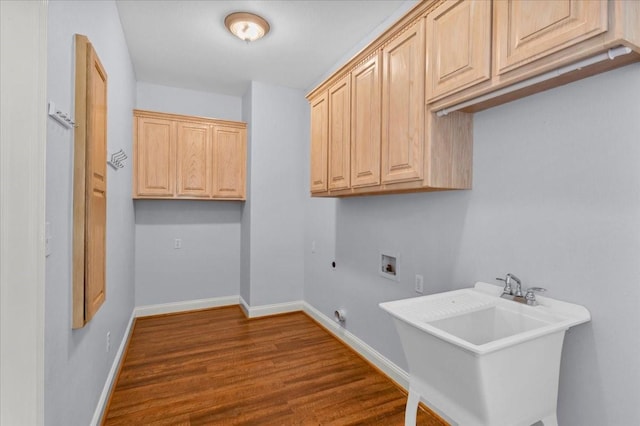 laundry area featuring baseboards, dark wood-type flooring, cabinet space, a sink, and washer hookup