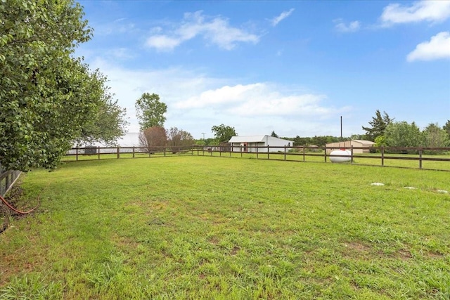 view of yard with fence and a rural view