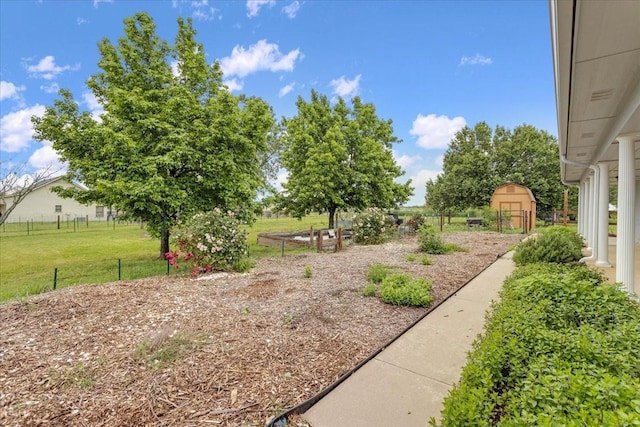 view of yard featuring fence, an outbuilding, a shed, and a garden