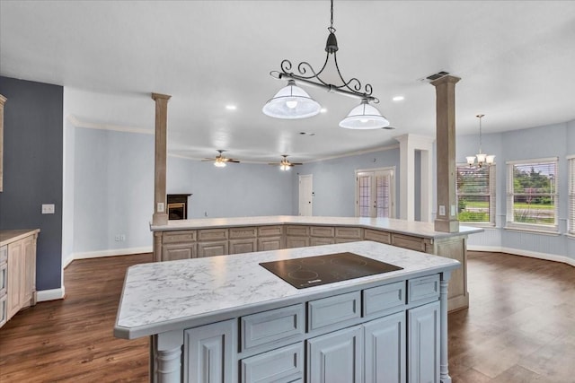 kitchen with dark wood-style flooring, light countertops, black electric cooktop, baseboards, and a kitchen island