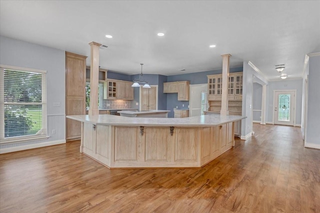 kitchen with ornate columns, light countertops, light brown cabinetry, and light wood-type flooring