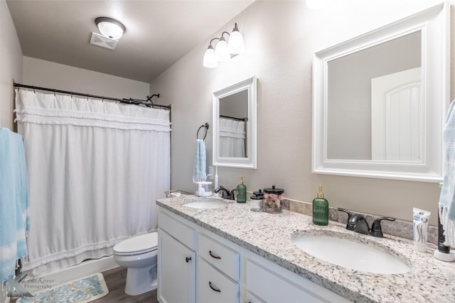 full bath with visible vents, a sink, double vanity, and toilet