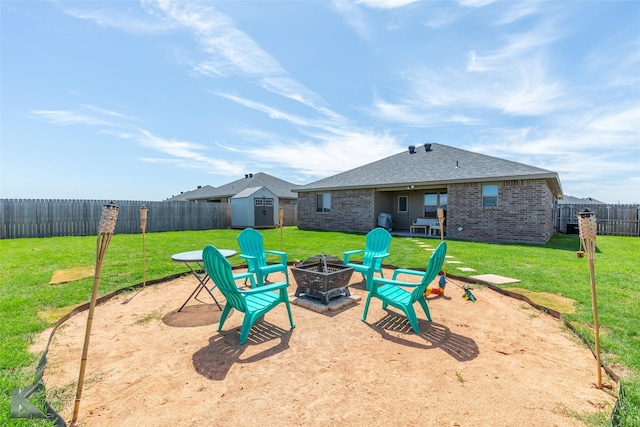 exterior space with a lawn, an outdoor structure, a fenced backyard, a storage unit, and a fire pit