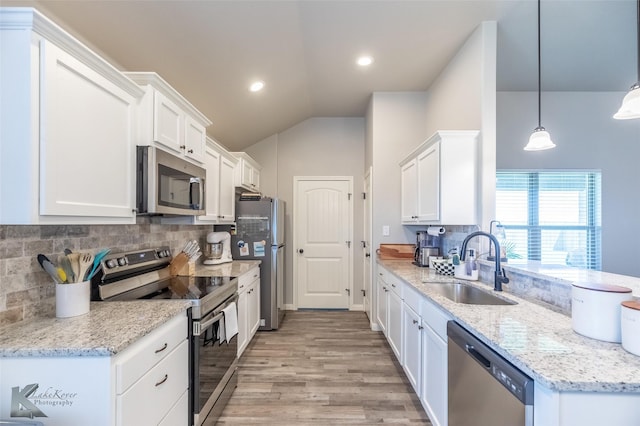 kitchen featuring lofted ceiling, white cabinets, a sink, light wood finished floors, and stainless steel appliances