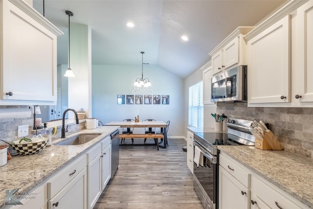 kitchen featuring decorative backsplash, lofted ceiling, a sink, light wood-style flooring, and appliances with stainless steel finishes