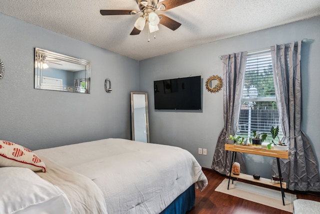 bedroom with dark wood-type flooring, a textured ceiling, ceiling fan, and baseboards