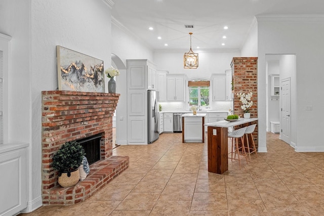 10535 Longfellow Trce, Shreveport, LA 71106 - kitchen with crown molding, appliances with stainless steel finishes, a kitchen island, light countertops, and a brick fireplace